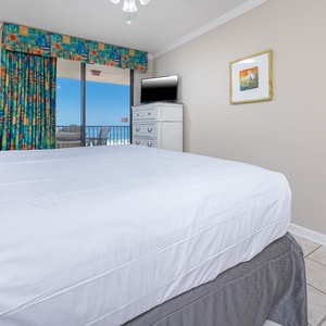 Experience restful nights in this master suite, featuring a king bed and vibrant curtains with a view of the balcony