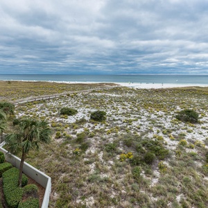 Overlooking the sand dunes that lead to the beach, the pool area and jetties at the pass can be seen in the distance