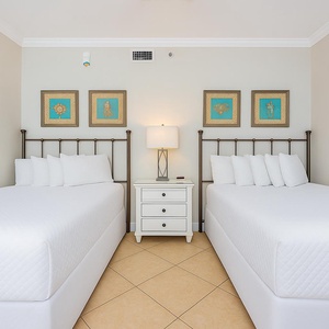 Relax in the cozy guest bedroom with plush full beds and vibrant artwork, perfect for restful nights after a beach day