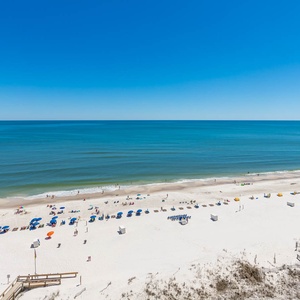 Vibrant beach umbrellas dot the pristine white sand, inviting relaxation under the clear blue sky and tranquil waters