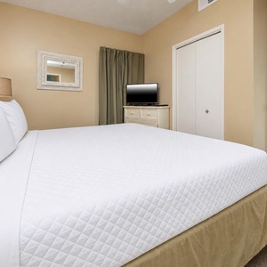 Relax in the inviting bedroom featuring a comfortable king bed, a TV, and soft decor accents