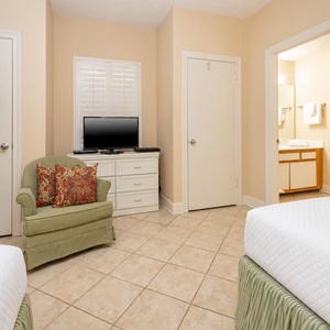 Relax in this cozy guest room featuring double beds, a TV, and a comfortable chair for unwinding
