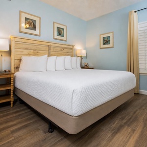 Bright blue walls complement the rustic wooden headboard and cozy bedding in this inviting bedroom with a mounted TV