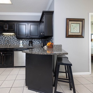 Prepare meals in the stylish kitchen featuring sleek black cabinets, granite countertops, and stainless appliances