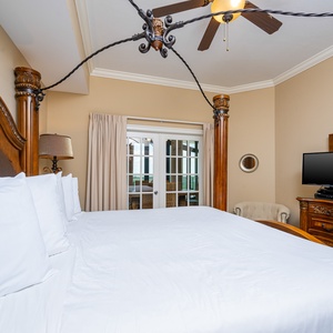 The master bedroom features a plush king bed, a TV for entertainment, and access to a serene outdoor view 