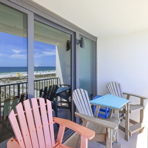 Enjoy a beachfront view from this balcony, featuring colorful seating and a cozy atmosphere for relaxation