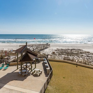 This balcony view showcases a serene beach, perfect for relaxation with outdoor seating and a glimpse of the pool area