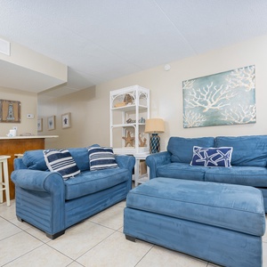 The living area features plush blue seating, coastal decor, and a convenient bar area for relaxation and entertainment