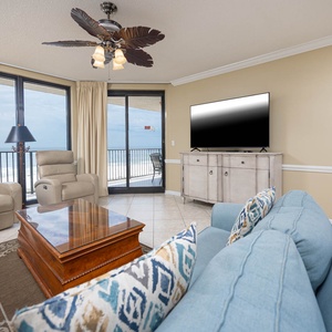 Relax in the inviting living area, featuring comfortable seating and a large TV, with views of the coast beyond