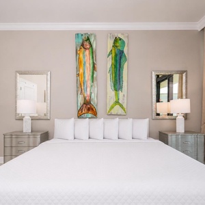 Serene master bedroom with a large king bed, vibrant fish artwork, and stylish nightstands
