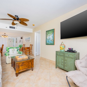 Bright and inviting living area featuring a large TV, cozy seating, and tropical decor for a relaxing getaway