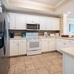 Prepare meals in this kitchen featuring white and stainless appliances, ample counter space, and a coffee corner