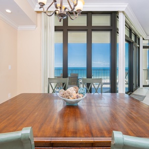Enjoy meals with a view of the coastline from this inviting dining area featuring a wooden table and coastal decor
