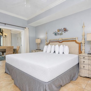 Inviting master bedroom featuring a plush king bed, elegant decor, and a view of the dining area through large windows