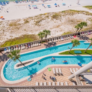 Experience the vibrant lazy river with winding waters and palm trees, just steps from the beach and colorful umbrellas
