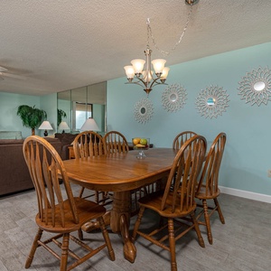 Dine comfortably at the wooden table surrounded by charming decor and a welcoming living area