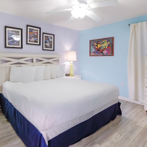 Brightly colored walls complement the king bed, accented by artwork and a cozy lamp in this cheerful bedroom