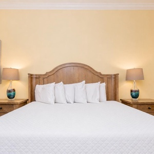 Relax in this inviting guest bedroom featuring a king bed, warm yellow walls, and charming coastal decor