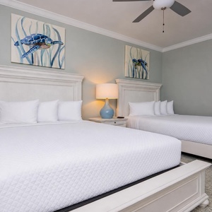 Rest in this tranquil guest bedroom featuring two queen beds, soft linens, and charming sea turtle art