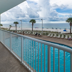 Enjoy a relaxing view from the balcony overlooking the pool and beach, with comfortable seating for unwinding