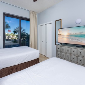Relax in this inviting guest bedroom with two comfortable double beds, a large TV, and views of palm trees