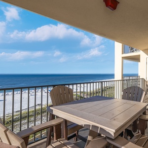 The spacious balcony features a dining table and chairs, offering a serene view of the beach and tranquil ocean waves