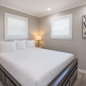 This bedroom features a comfortable bed, soft lighting, and a charming wall art piece, creating a serene retreat
