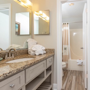 The master bathroom features a granite countertop with dual sinks, ample towels, and a tub/shower combo