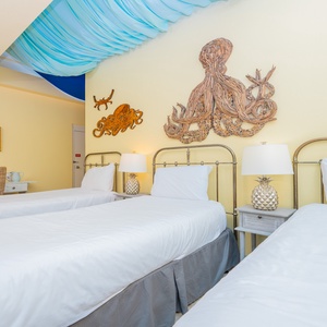 Three twin beds with nautical decor and charming pineapple lamps on nightstands are featured in the indoor master patio
