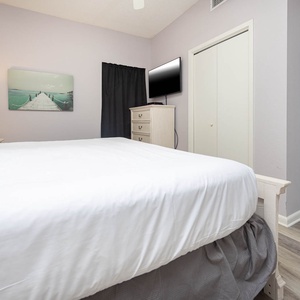 Inviting bedroom featuring a plush bed, soft lighting, and a mounted TV, creating a relaxing retreat for guests