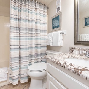 The bathroom features a stylish granite countertop, shower with a striped curtain, and fresh towels for a relaxing experience
