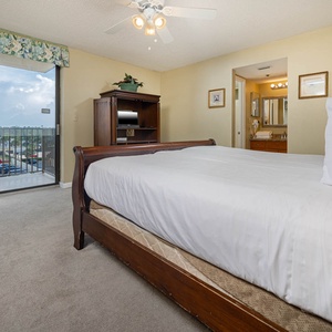 The master bedroom features a king bed, a cozy chair, and a sliding door leading to a balcony with a view