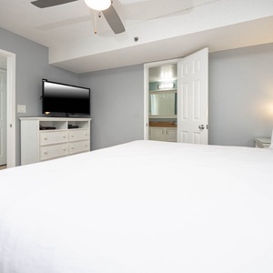Bright and inviting master bedroom featuring a cozy king bed, flat-screen TV, and an ensuite bathroom for added convenience