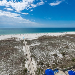 Stunning view of the beach and turquoise gulf waters, featuring a boardwalk leading to the shore