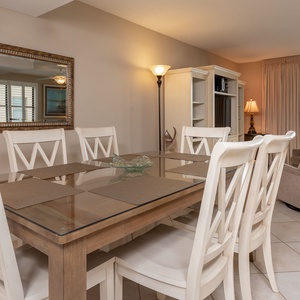 Bright dining area featuring a glass-top table and white chairs, perfect for enjoying meals with a view