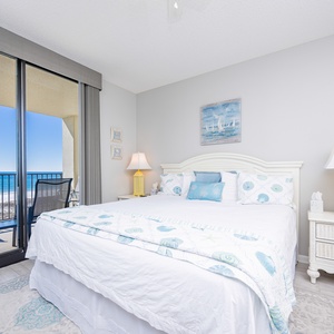Cozy master bedroom featuring a king bed with beachy decor and a balcony view of the tranquil gulf waters
