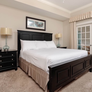 The master bedroom features a plush king bed, stylish black furnishings, and a cozy atmosphere complementing your stay