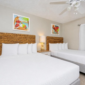 Two double beds in the guest suite await your restful nights with serene artwork and soft lamp glow nearby
