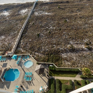 Pool area featuring a large swimming pool, kiddie pool, and lounge chairs, leading to a scenic beach access path