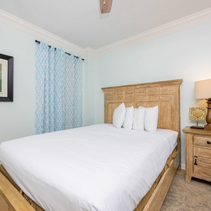The guest bedroom features a wooden bed with white linens, soft blue curtains, and a serene atmosphere perfect for relaxation