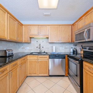 Kitchen features wooden cabinetry, granite countertops, and a breakfast bar with seating, leading to a cozy living area
