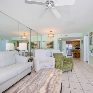 Cream sofa and cozy chairs face the big screen where your family watches movies after beach days