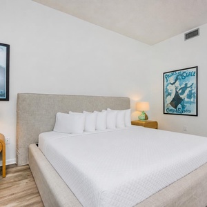 Guest bedroom featuring a plush king bed, two twin bunks, stylish artwork, and warm lighting for a cozy retreat