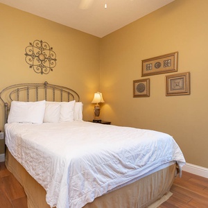 This cozy guest bedroom features a comfortable bed, warm beige walls, and decorative accents, perfect for a restful getaway