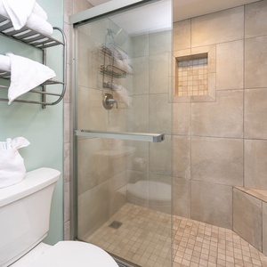 The master bathroom features a tile walk-in shower, stylish tile accents, and neatly arranged towels on a rack