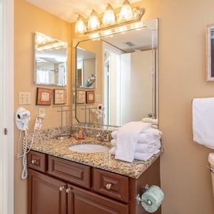 Bathroom featuring a granite vanity, ample towels, and decorative artwork, creating a welcoming atmosphere