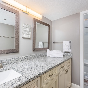 Granite countertops complement the stylish dual mirrors and fresh towels in this inviting master bathroom space