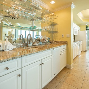 Relax with a drink from the sleek wet bar area with an ice maker, granite countertop, and glassware display