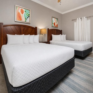Relax in this inviting guest bedroom featuring two queen beds, stylish decor, and a warm vibe for restful nights