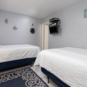 This inviting room features two comfortable beds, a wall-mounted TV, and beach-themed decor for a relaxing stay